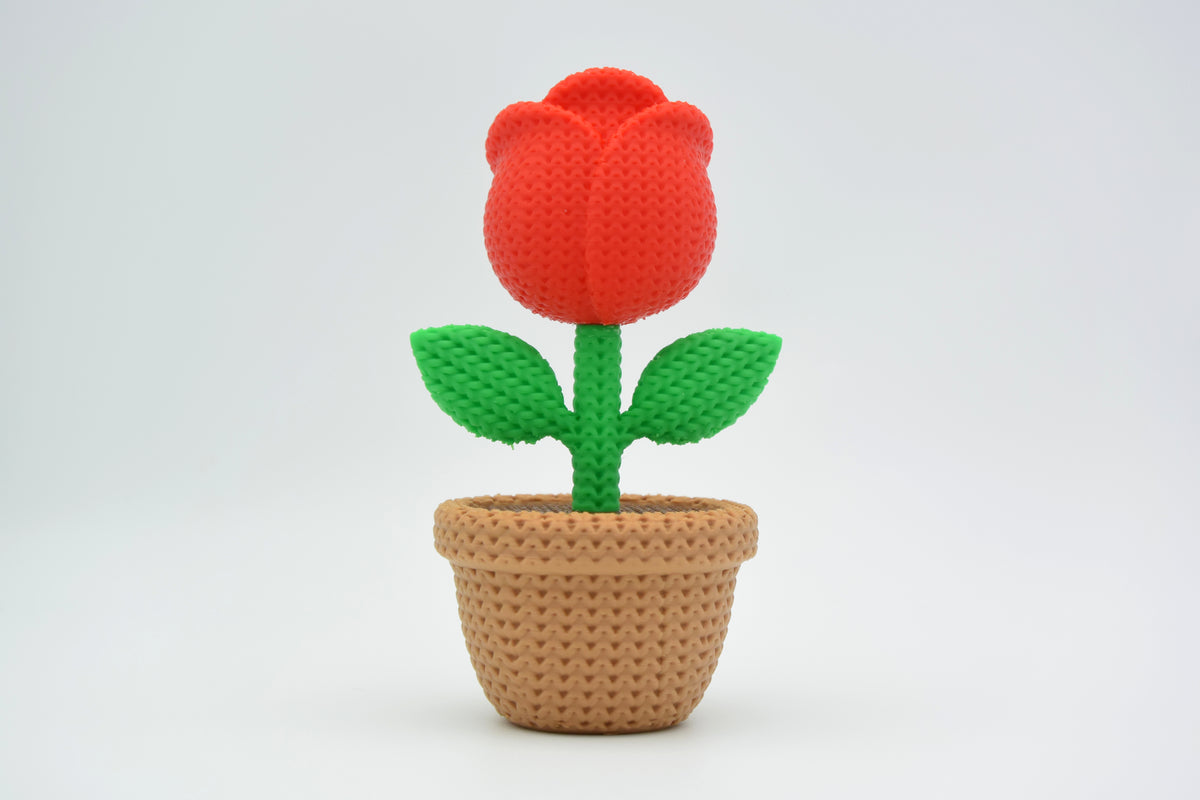 Gros plan d'une rose tricotée décorative aux pétales doux dans des tons rouges chaleureux