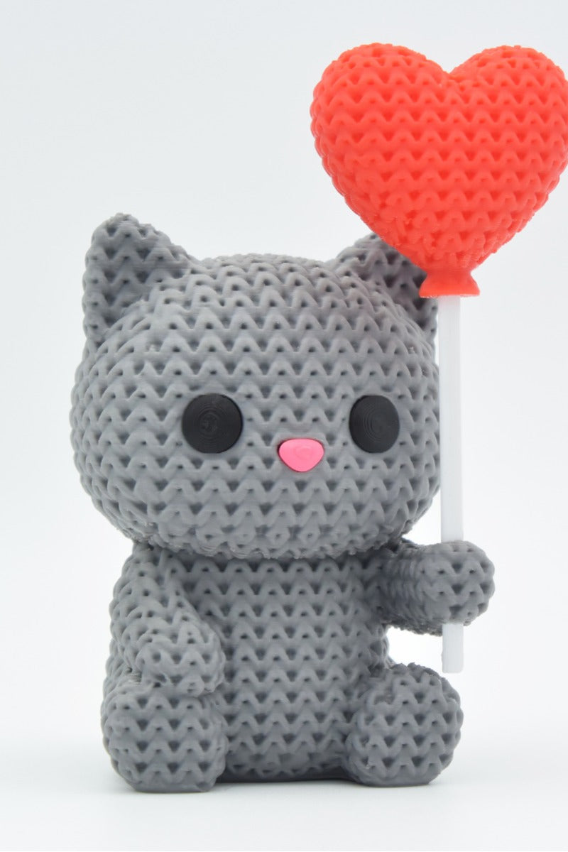Gros plan d'une figurine de chat tricoté avec ballon cœur dans des couleurs chaudes