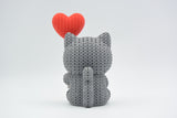 Gros plan d'une figurine de chat tricoté avec ballon cœur dans des couleurs chaudes