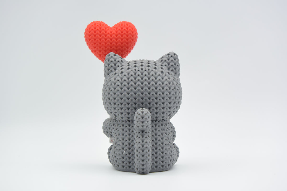 Gros plan d'une figurine de chat tricoté avec ballon cœur dans des couleurs chaudes