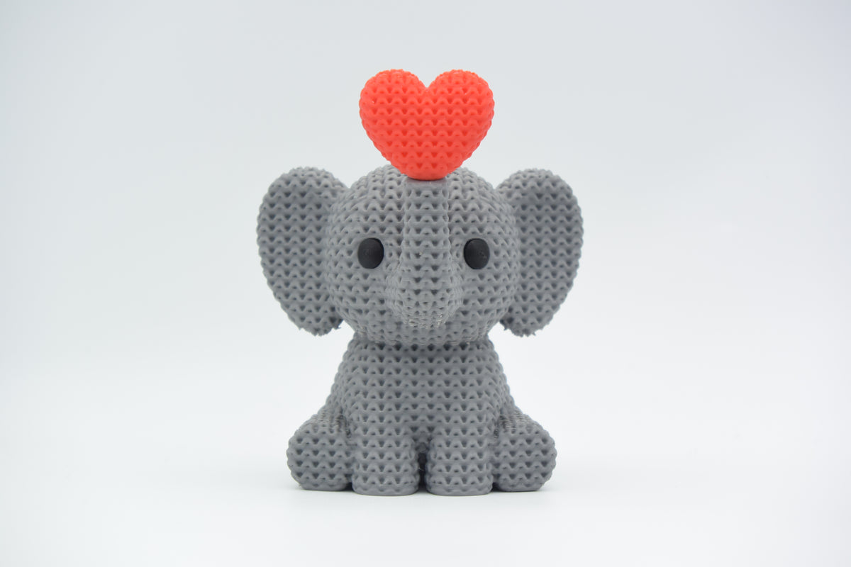 Éléphant tricoté soufflant un cœur, sur une étagère en bois avec une déco scandinave