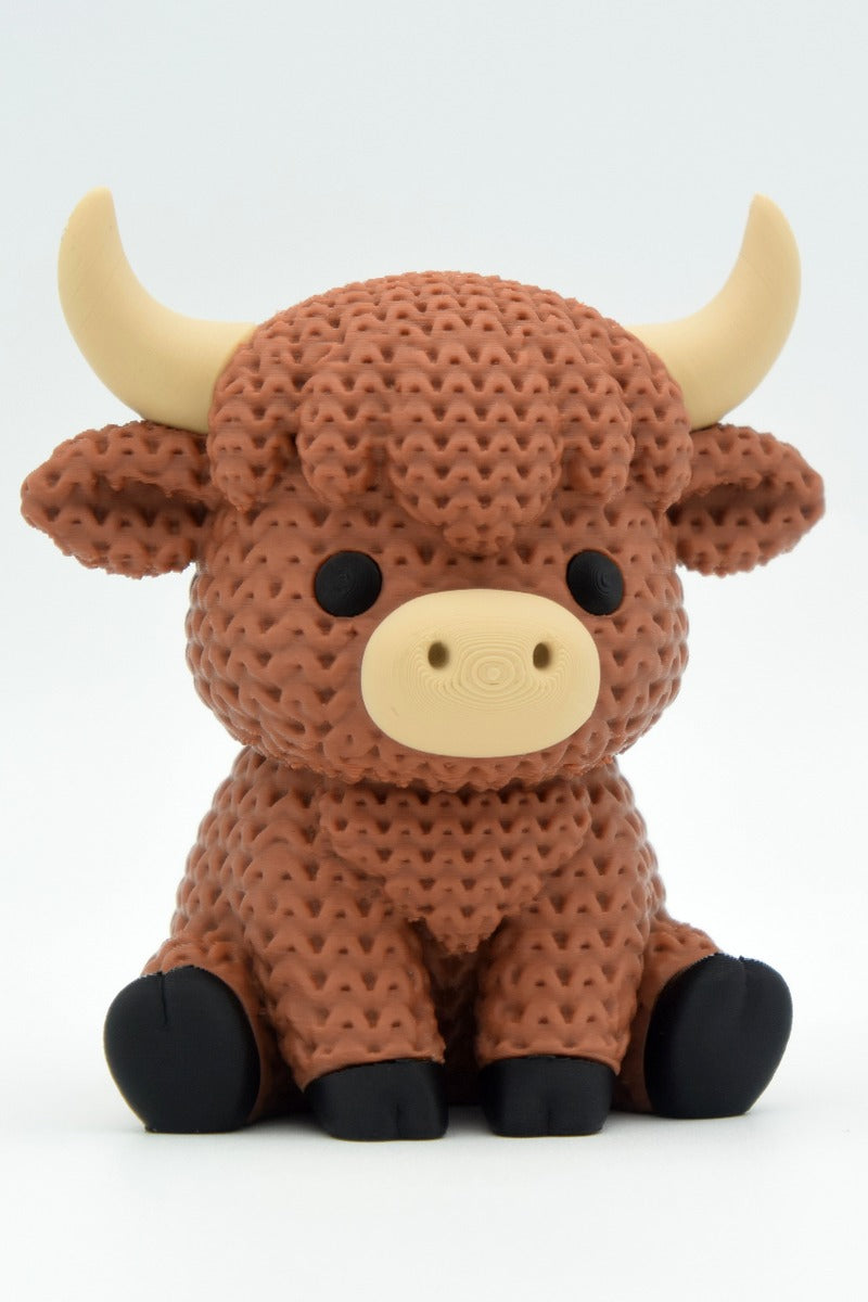 Gros plan d'une vache Highland tricotée au pelage crocheté et aux petites cornes sculptées