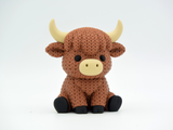 Gros plan d'une vache Highland tricotée au pelage crocheté et aux petites cornes sculptées
