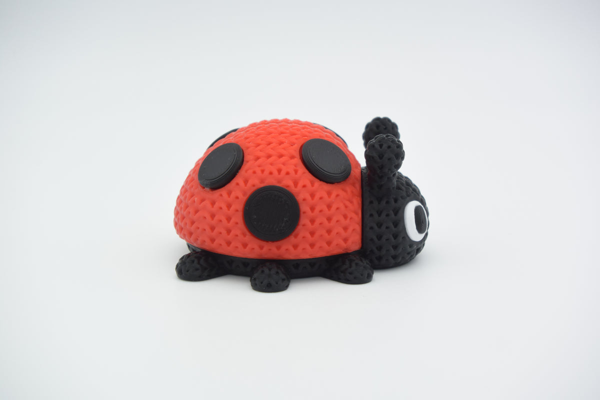 Petite coccinelle façon tricot sur une étagère en bois près d'une plante et d'accessoires déco neutres