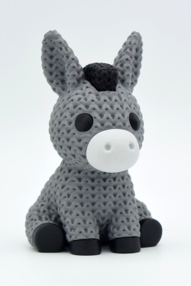 Gros plan d'une figurine d'âne tricoté, aspect crocheté, sur fond neutre