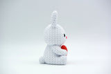 Lapin tricoté avec cœur sur une étagère en bois avec fleurs de printemps et déco de Pâques