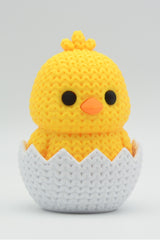 Gros plan d'une décoration de Pâques poussin sortant de l'œuf, douce texture tricotée jaune pâle
