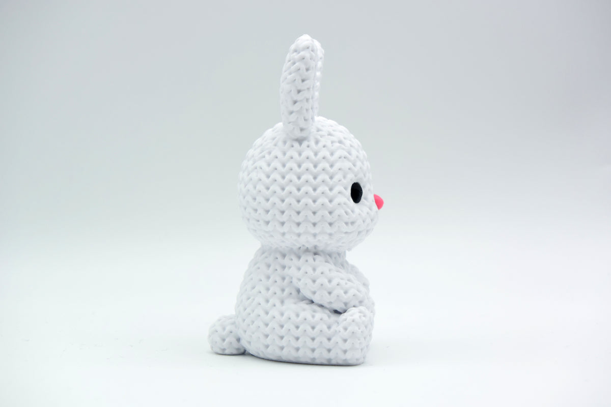 Gros plan d'un petit lapin tricoté à la douce texture crochetée sur fond blanc