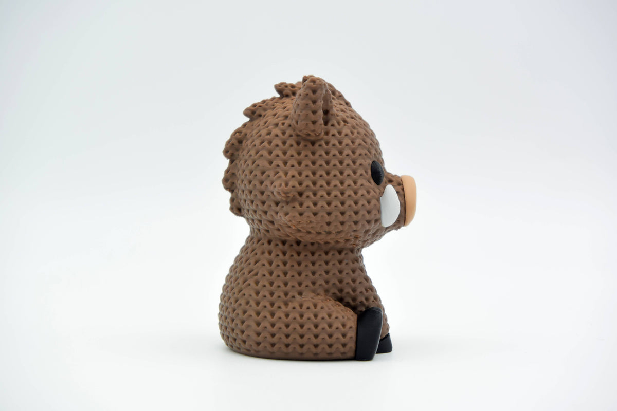 Figurine de sanglier tricotée sur une étagère en bois à côté d'une déco naturelle