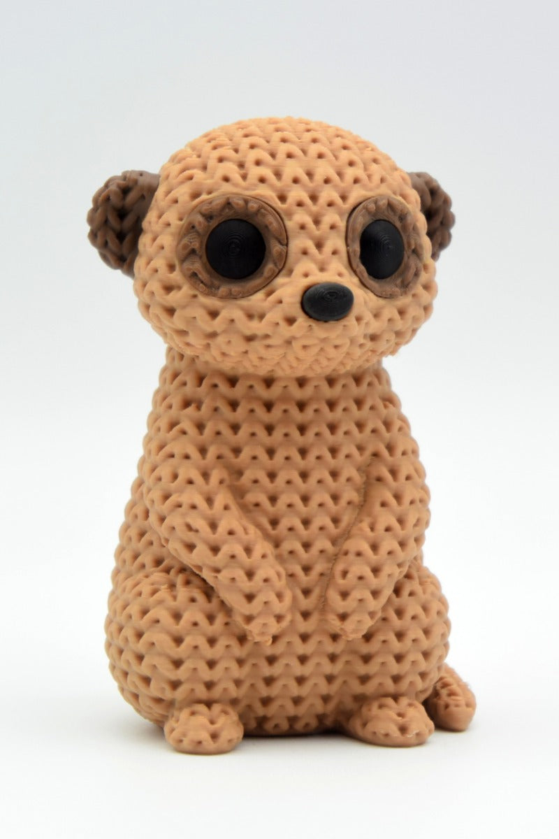 Gros plan d'une figurine de suricate tricoté à texture crochetée, debout sur fond blanc