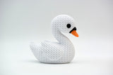 Cygne blanc façon tricot sur une étagère en bois près de fleurs séchées et de déco neutre