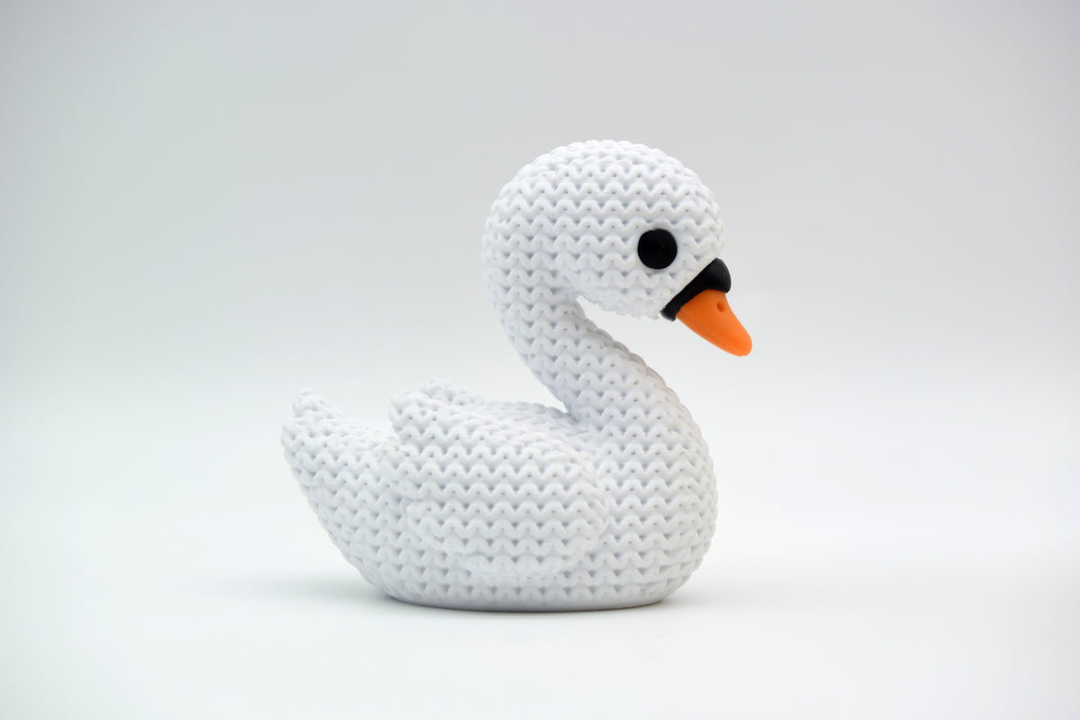 Cygne blanc façon tricot sur une étagère en bois près de fleurs séchées et de déco neutre
