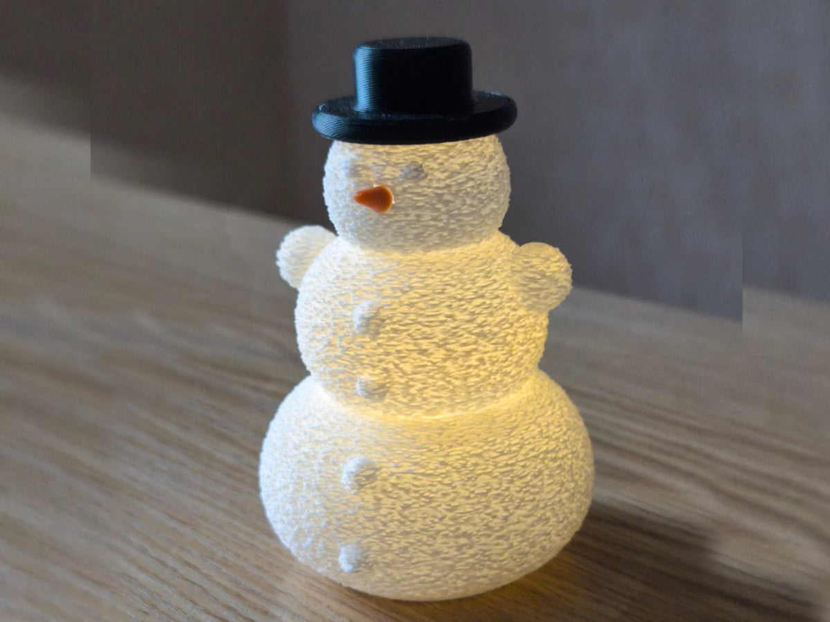 Bonhomme de neige avec chapeau et nez au-dessus d'une bougie LED