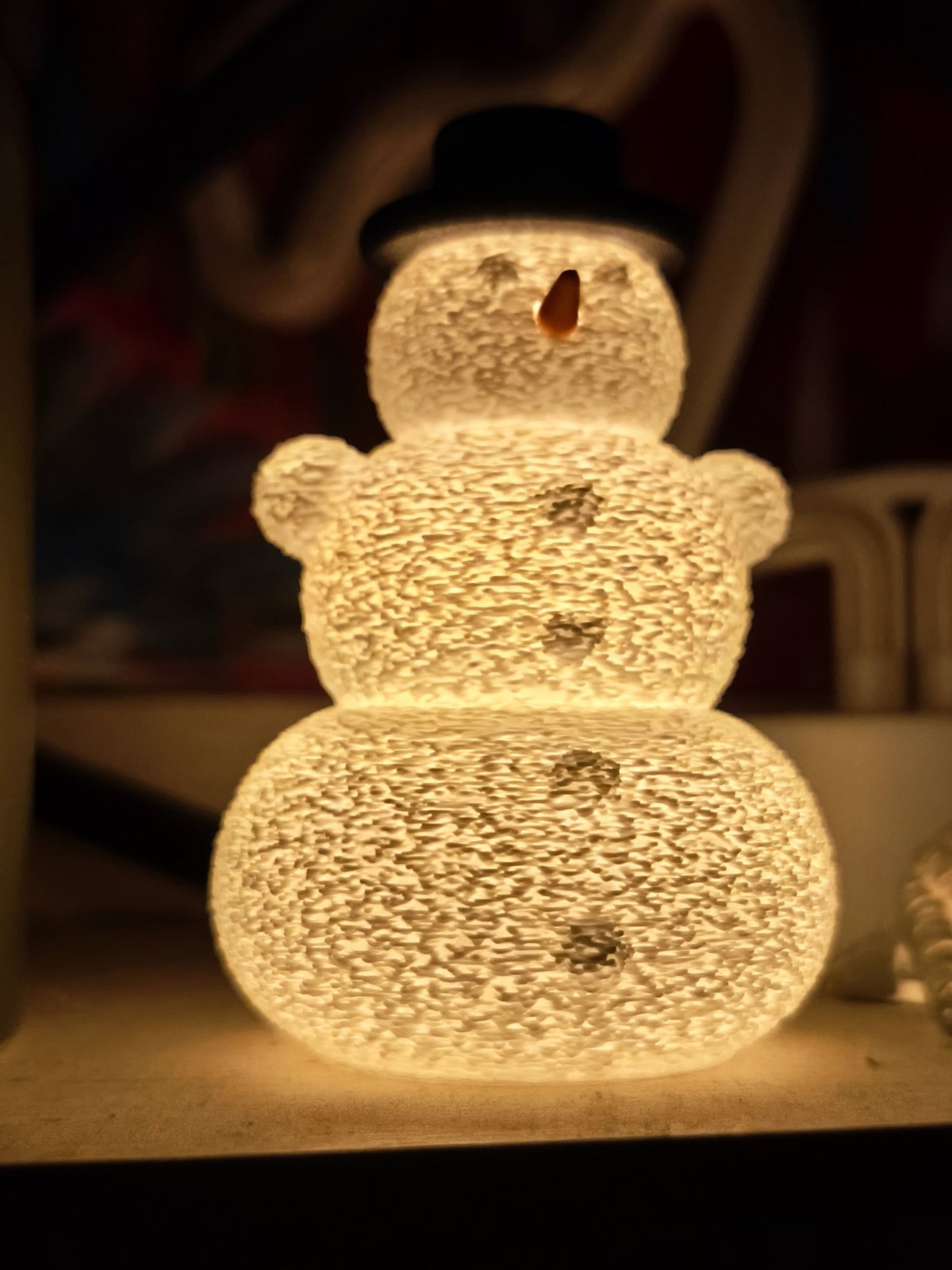 Bonhomme de neige avec chapeau et nez au-dessus d'une bougie LED